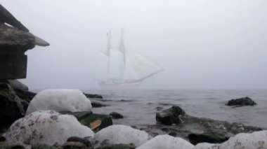 zeilboot in volledige zeil komt uit mist