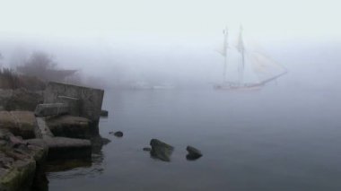 zeilboot in volledige zeil komt uit mist