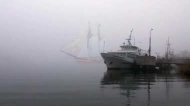 zeilboot in volledige zeil komt uit mist