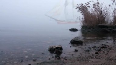 zeilboot in volledige zeil komt uit mist