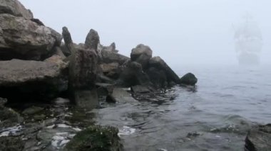zeilboot in volledige zeil komt uit mist
