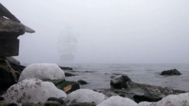 zeilboot in volledige zeil komt uit mist