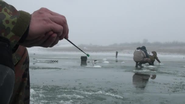 穴の近くの氷の冬の川の釣りロッド — ストック動画