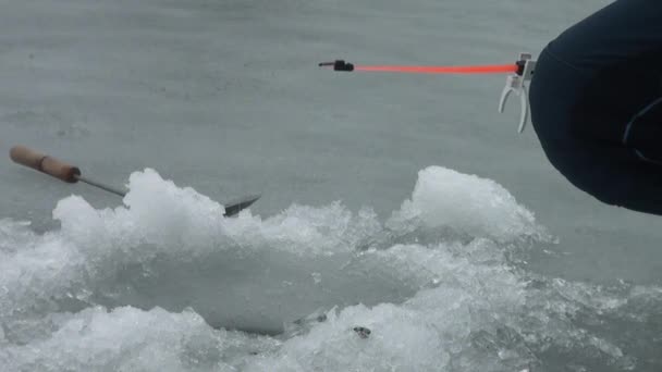 Caña de pescar en el río en invierno en el hielo cerca del agujero — Vídeos de Stock