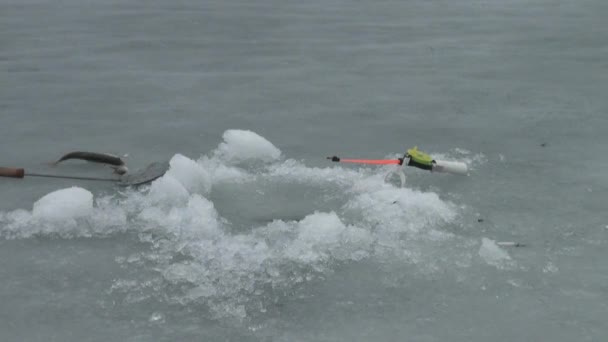 Fiskestang på elven om vinteren på isen nær hullet. – stockvideo