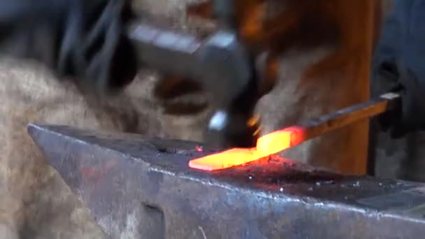 Blacksmith is hammering red-hot piece of iron — Stock Video