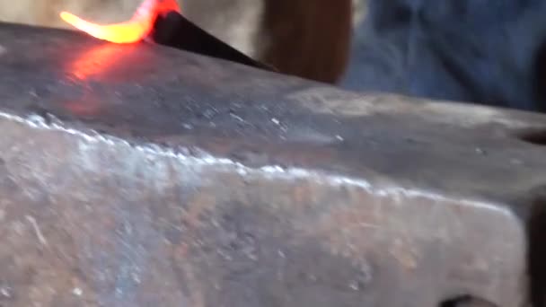 Blacksmith is hammering red-hot piece iron — Stock Video