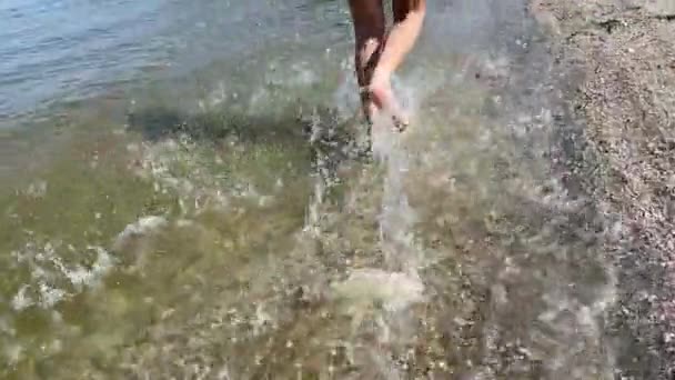 Visão Traseira Das Pernas Menino Corre Longo Praia Salpicando Gotas — Vídeo de Stock