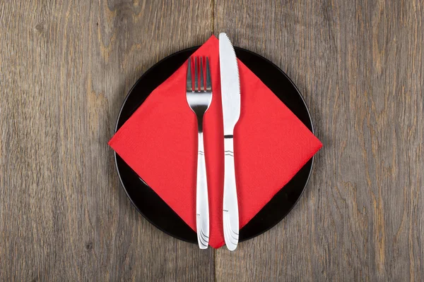 Πιρούνι, μαχαίρι και κόκκινο χαρτοπετσέτα στο μαύρο πιάτο — Φωτογραφία Αρχείου