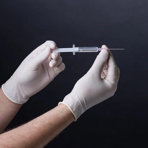 Hand in latex gloves with syringe — Stock Photo, Image