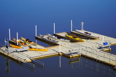 Set of colorful kayaks sitting on a dock by a lake