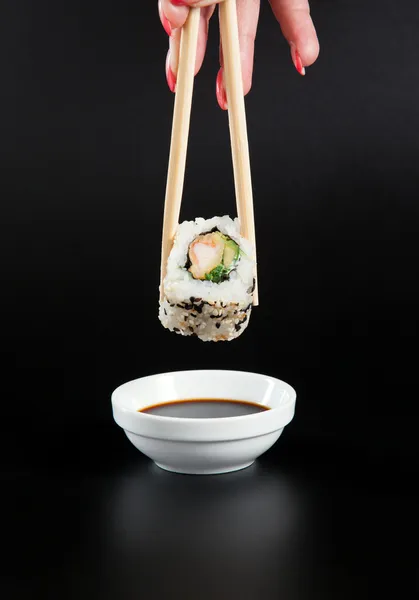 Tenir un rouleau de sushi, rouleau de sushi sur la sauce soja, nourriture japonaise . — Photo