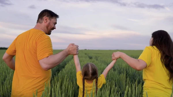 Happy family run through green field with wheat, childhood dream, wheat plantation for production of healthy food bread products, agricultural business, agriculture, mother father and little kid — Stock fotografie