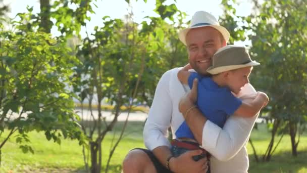 Fathers day, cheerful dad hugs his son and smiles on a walk, happy family, loving a boy, preschooler with a parent in the park, spending a day off with a kid, custody of a baby, affectionate childs — Stock Video