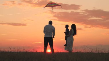 Mutlu aile günü, baba anne ve çocuk gün batımında gökyüzüne uçurtma uçurur, akşamları doğada çocukla oynar, aileyle vakit geçirmeyi sever, bebek büyütür ve geliştirir, neşeli bir hayat kurarlar..