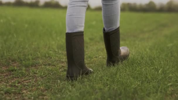 Un agronomo cammina lungo il sentiero verde in stivali di gomma, agricoltura, escursioni in scarpe turistiche, un viaggiatore viaggia all'aperto nella natura, un uomo in jeans su un prato, un agronomo si muove attraverso un campo — Video Stock