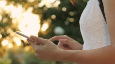 Gün batımında tablette çalışan bir kız, gün batımında bir alet ekranında, güneş ışığında, parmağınızı ekranda gezdirin, yakın plan yazın, iş kadını, online bir mağazada uzaktan sipariş verme konsepti