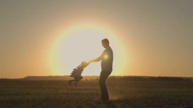 Silüet baba gün batımında havada çocuk daireler çiziyor, mutlu aile günü, babalar günü, babayla süper kahramanı oynamak güneş altında çocuk havada süzülüyor uçuşun keyfini çıkarıyor, çocukluk hayali kavramı, babayla fantezi kurma