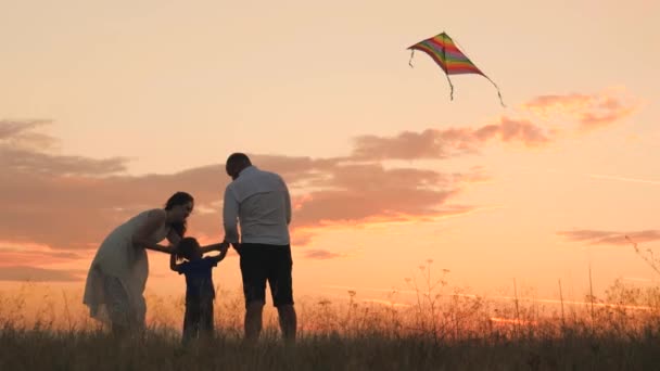 Gelukkige familiedag, vader moeder en kind vliegen een vlieger de lucht in bij zonsondergang, spelen 's avonds met kind in de natuur, houden van tijd doorbrengen met familie, opvoeden en ontwikkelen van baby' s, vrolijk leven. — Stockvideo
