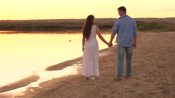 Ein Mann und eine Frau spazieren am Strand bei Sonnenuntergang am Himmel entlang, romantische Beziehung zweier Menschen, glückliche Familie, fröhliche Menschen kommunizieren gerne, verbringen ein unbeschwertes Wochenende zusammen — Stockvideo