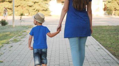 Anne küçük oğlunu şehir parkına götürüyor, mutlu aile, çocukla tatil günü, yaz gezisi çocukla, el ele, birbirine dikkat, çocuk iyi vakit geçiriyor, çocukluk hayali