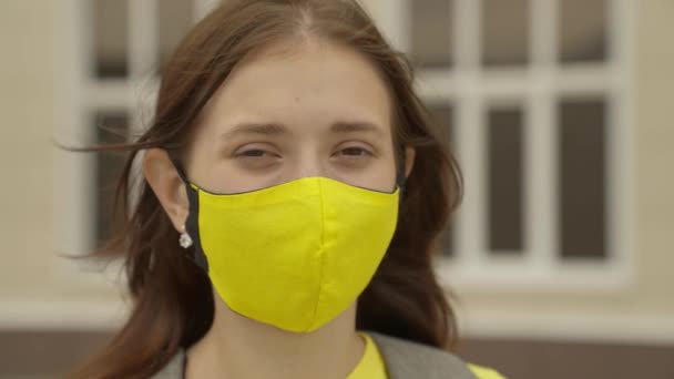 En vuxen skolflicka sätter på sig en ansiktsmask och ler, pandemi 2022, filtrerar luft för lungornas luftvägar, förhindrar COVID-19-infektion, skyddar en person från coronavirus med maskläge — Stockvideo
