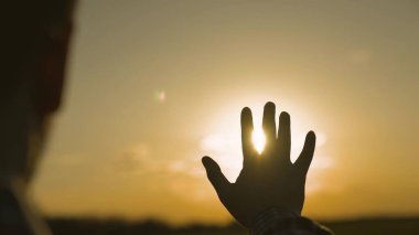 İnsan eli gün batımında gökyüzünde, mutluluk rüyası, güneş ışınlarında meditasyon, parlak turuncu ışık, tatilde seyahat, doğa ve rahatlığın ahengi, gün doğumuyla tanışma