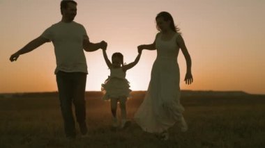 Anne ve babasıyla küçük bir çocuk gün batımında sahada koşuyor, mutlu aile, ebeveynlerle eğlenceli hayat, anne ve baba çocuk yürüyüş için koşuyor, aktif yaşam tarzı, bebek bakımı, aşk ve bakım, takım çalışması.