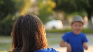 Küçük çocuk annesiyle tanışmak için koşuyor ve sarılıyor, mutlu bir aile, annesinin kollarında neşeli bir çocuk, yeni ebeveynler tarafından evlat edinilmiş bir çocuk, anneler günü, mutlu bir çocukluk günü, sevgili annesine olan sevgisi.