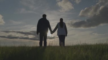 Tarım, siluet adam ve kadın el ele tutuşuyor ve gün batımında yükseliyor, tarlada iş yapıyor, çiftçi çalışıyor, takım çalışması, iş adamlarının güven ve eşitliği, tarım uzmanları konsepti