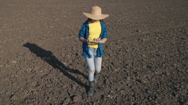 Tabletli bir çiftçi tabletle tarlada yürüyor, bir tarlada çalışıyor, çiftçilik yapıyor, tarım yapıyor, bir tarım uzmanı toprağın organik topraklarına tohum ekmeye hazırlanıyor, iş üretimi yapıyor.