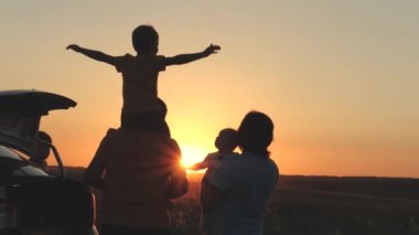 Mutlu aile gün batımında arabayla seyahat, anne baba ve çocuk arabayla turist gezisi, genç çiftin aile arabası, çocukluk hayali, baba omuzlarındaki küçük çocuk uçmayı hayal ediyor, çocuk pikniği.