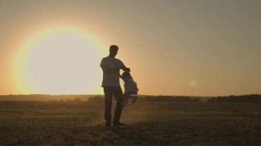 Nazik bir baba gün batımında bir çocuğu döndürüyor, mutlu bir ailenin silueti, gün ışığında babasıyla oynayan neşeli bir çocuk, babalar günü, çocuk yolculuğu, ebeveynleriyle yürümek, iyi bir hayat.