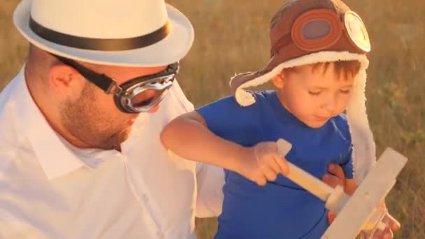 Vader speelt met zijn zoon in de piloot, droom om te vliegen, vaders dag, gelukkig gezin, jongen met vader heeft plezier op de speelplaats en lacht, kind in helm fantaseert op de speelplaats met zijn ouders zitten in de zon — Stockvideo