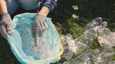 El poşete plastik bir şişe koyar, işlenebilen çöp, eko, çevreyi temiz, yeşil gezegeni güvenli, doğa orman ekosistemi, çevre koruma sorunu, hayır işleri