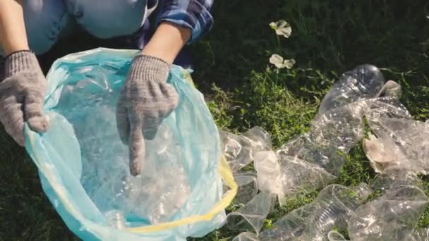Ręka wkłada plastikową butelkę do torby, śmieci do przetworzenia, eko, dbać o czystość środowiska, ekologiczną planetę, ekosystem leśny, problem ochrony środowiska, działalność charytatywna — Wideo stockowe