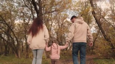 Mutlu bir aile, anne ve babasıyla küçük bir çocuk sonbahar parkında yürüyorlar. Ormanda, sonbahar doğasında, açık havada, anne ve babayla eğlenceli çocuk hayatı, küçük bir kızın velayeti,