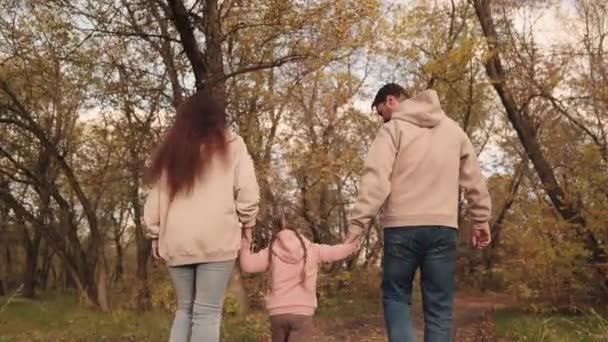 Szczęśliwa rodzina, małe dziecko z tatą i mamą spacerują w jesiennym parku w lesie, jesienna przyroda, na świeżym powietrzu, zabawne życie dzieci z ojcem i matką, opieka rodzicielska nad małą dziewczynką, wychowywanie córki — Wideo stockowe