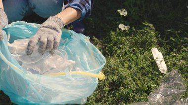 El poşete plastik bir şişe koyar, işlenebilen çöp, eko, çevreyi temiz, yeşil gezegeni güvenli, doğa orman ekosistemi, çevre koruma sorunu, hayır işleri