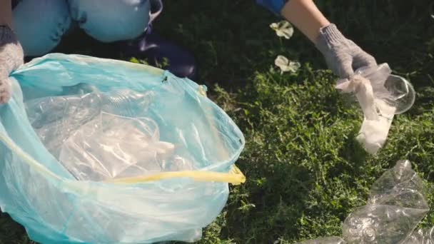 Hand zet een plastic fles in een zak, afval voor verwerking, eco, houdt het milieu schoon, groene planeet veilig, natuur bos ecosysteem, milieubescherming probleem, liefdadigheid activiteiten — Stockvideo