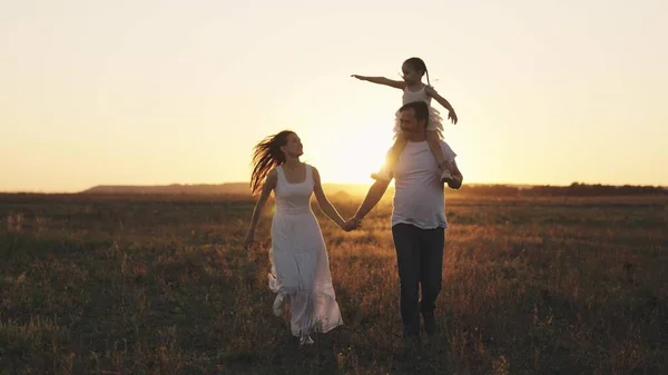 Father mother and child run at sunset in sky, silhouette of happy family, little kid sits on dad shoulders, family trip, fun life parents and daughter, play outdoor nature superhero, weekend together — Stock Photo, Image