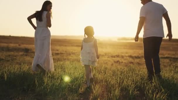 Una niña riendo corre con sus padres al atardecer, una familia feliz, un sueño de infancia, un niño corriendo al sol con mamá y papá, jugando a ponerse al día con el niño, padre y madre con la hija bebé — Vídeo de stock