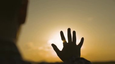 İnsan eli gün batımında gökyüzünde, mutluluk rüyası, güneş ışınlarında meditasyon, parlak turuncu ışık, tatilde seyahat, doğa ve rahatlığın ahengi, gün doğumuyla tanışma