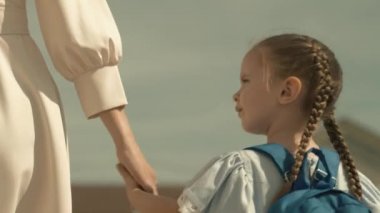 Anne küçük bir çocuğu ilkokulun birinci sınıfına götürüyor, okul çantası bir kızın omuzlarında, mutlu bir aile, okul bahçesinde acele bir ders, sırt çantalı bir çocuk eğitim alacak.