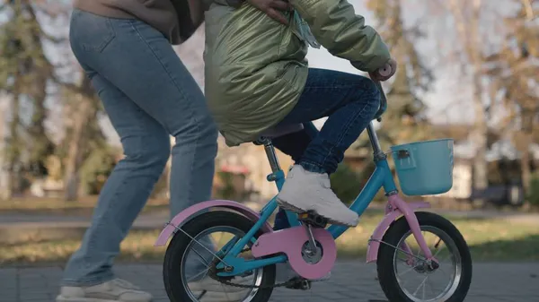 Niño aprende a montar en bicicleta de dos ruedas, el niño juega con su madre en el parque de la ciudad, familia feliz, madre, divertirse con el bebé en la calle, pedales de giro y ruedas rápidamente, sueño de la infancia para aprender paseo — Foto de Stock