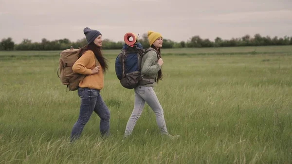 Las niñas felices viajan con mochilas de senderismo, diversión fin de semana con bolsas de viaje, estilo de vida activo al aire libre, recreación de grupo femenino, viajeros hipster durante miles de años, libre movimiento en busca de —  Fotos de Stock