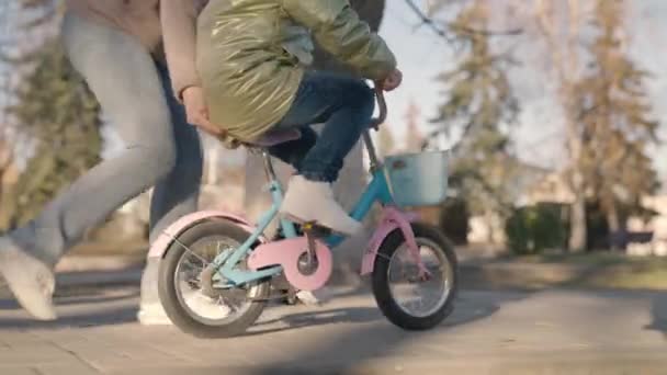 Niño aprende a montar en bicicleta de dos ruedas, el niño juega con su madre en el parque de la ciudad, familia feliz, madre, divertirse con el bebé en la calle, pedales de giro y ruedas rápidamente, sueño de la infancia para aprender paseo — Vídeos de Stock