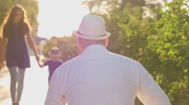 Oğlan gün batımında babasına sarılmak için koşar, mutlu aile, küçük oğlu güneş ışığında sevgili babasının kollarında, annesi ve çocuğu parkta yürüyüş, aşk hayatı, tanışma ve eğlenme, aile tatili