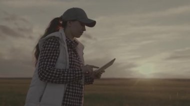Gün batımında tablette çalışan bir çiftçi, elinde bir aletle tarlada yürüyen bir tarım mühendisi, tarım ekinlerinde yazı yazan, ekin, tarım, arazi üzerinde iş üretimi yapan bir çiftçi.