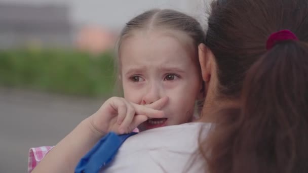Dziecko płacze przytulając matkę, małe zdenerwowane dziecko spada łzy na jej ramiona matki, kobieta uspokaja swoją poplamioną łzami córkę, łzy z jej oczu spływają po twarzy dziewczyny, dziecinne poczucie winy — Wideo stockowe